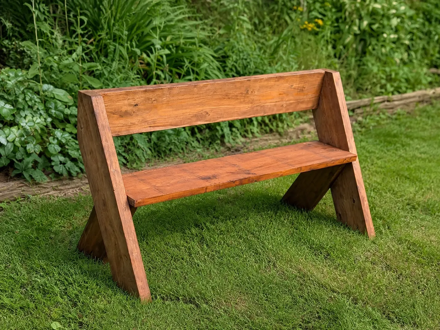 Simple handcrafted wooden garden bench with angled legs