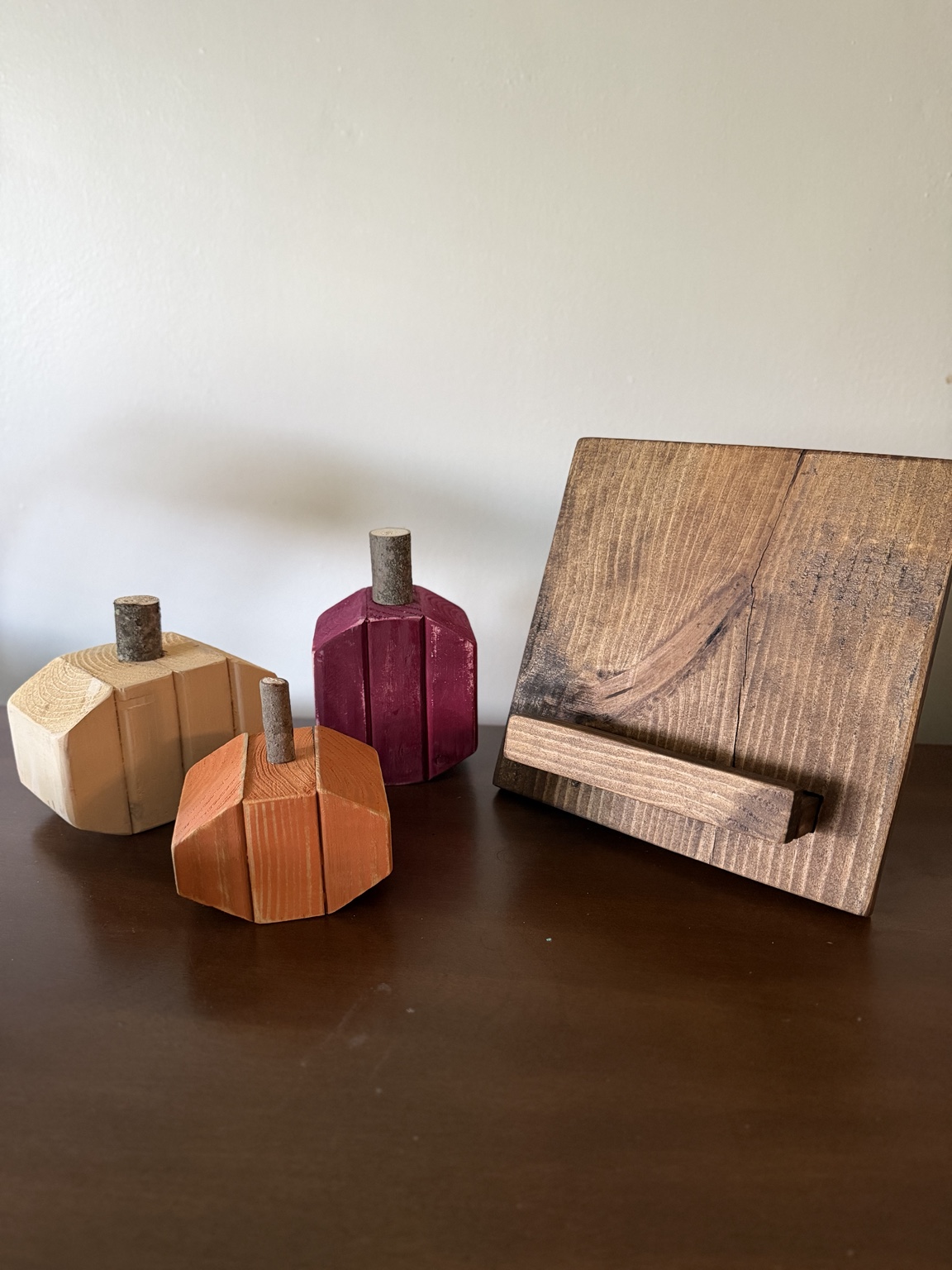 Handcrafted wooden pumpkins in autumn colors beside a recipe holder
